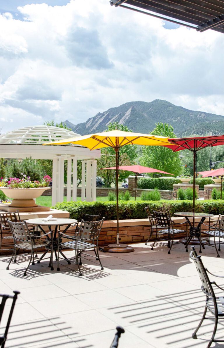 View of outdoor patio seating with sun umbrellas and mountains int he background