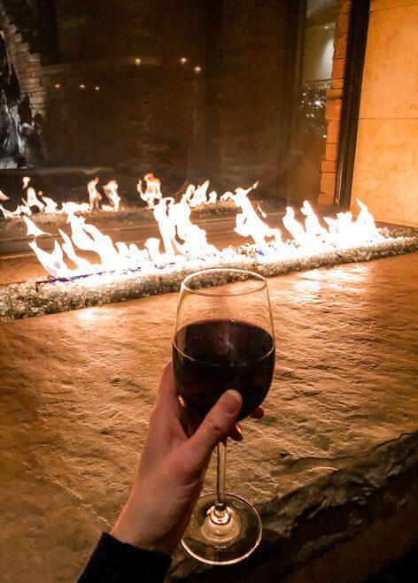 glass of red wine in front of the great room lobby fireplace